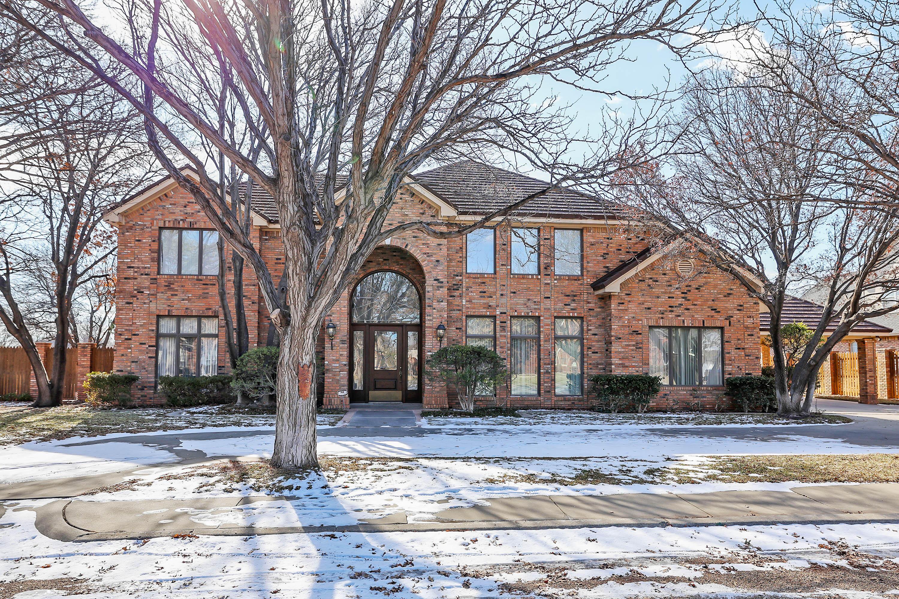 a front view of a house with a yard covered with snow and trees