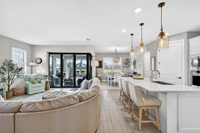 a kitchen with a sink a kitchen island stainless steel appliances and living room view