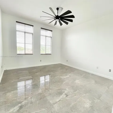 an empty room with windows and ceiling fan