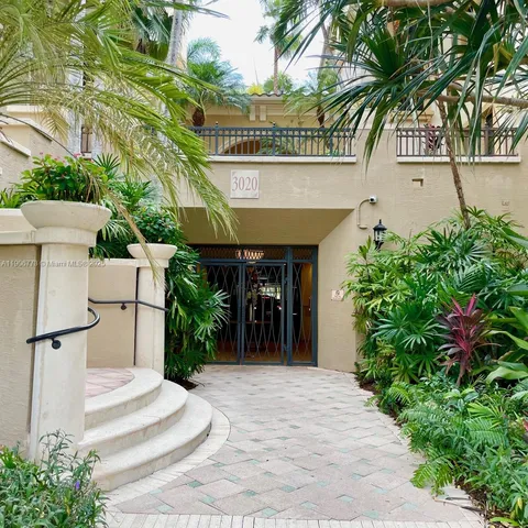 a view of a white house with potted plants and a lawn chairs