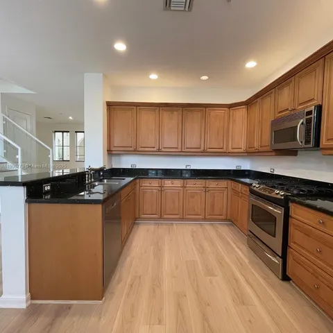 a large kitchen with stainless steel appliances granite countertop a stove a sink dishwasher and a refrigerator