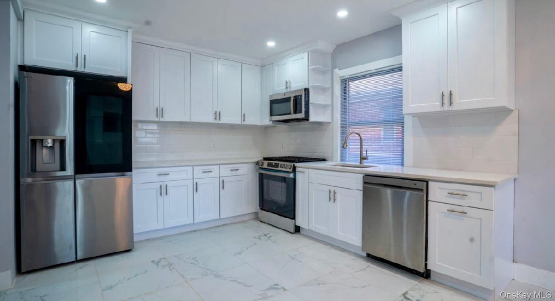 113-40 198th Street Queens, NY 11412 - Photo 7 of 20 a kitchen with white cabinets and stainless steel appliances