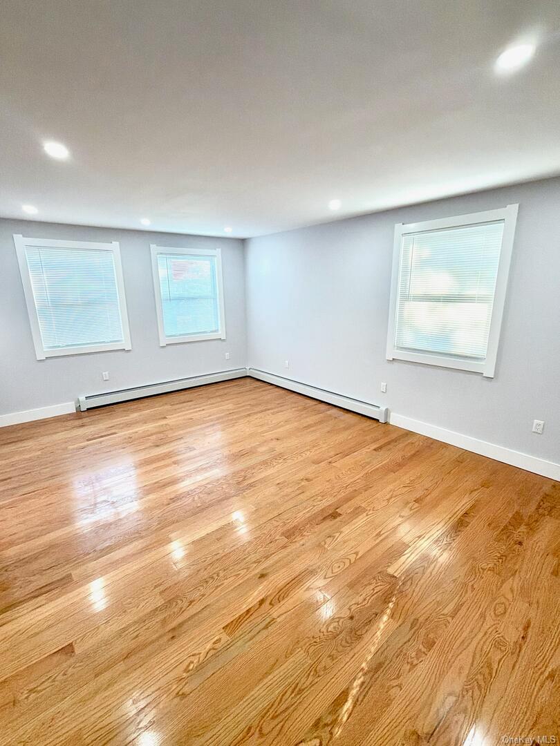 113-40 198th Street Queens, NY 11412 - Photo 9 of 20 an empty room with wooden floor and windows