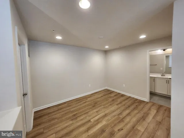 a view of empty room with wooden floor and kitchen