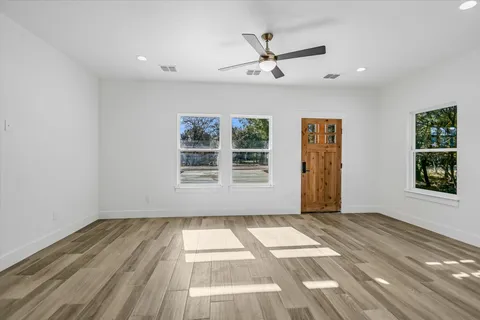 a view of an empty room with a window and wooden floor