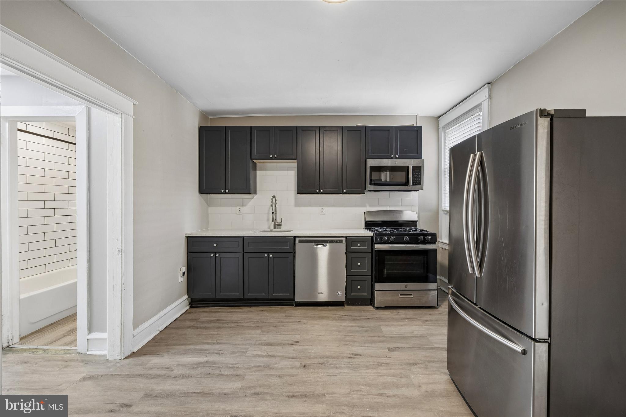 1117 Rosalie Street, Unit 1 Philadelphia, PA 19149 - Photo 11 of 30 a kitchen with granite countertop a refrigerator and a stove top oven
