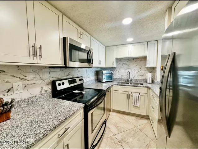 a kitchen with stainless steel appliances granite countertop a stove a sink dishwasher a refrigerator oven and a stove