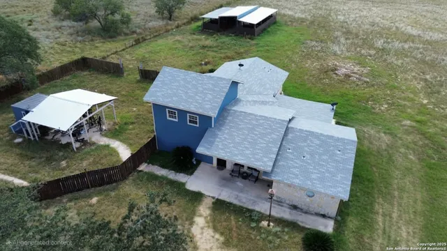 an aerial view of a house with swimming pool and a yard
