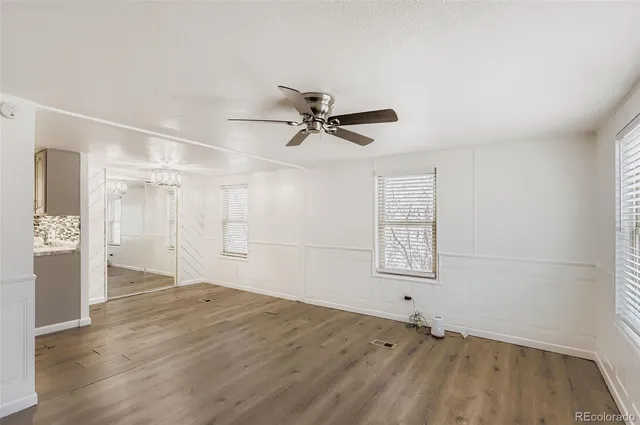 a view of empty room with wooden floor and ceiling fan
