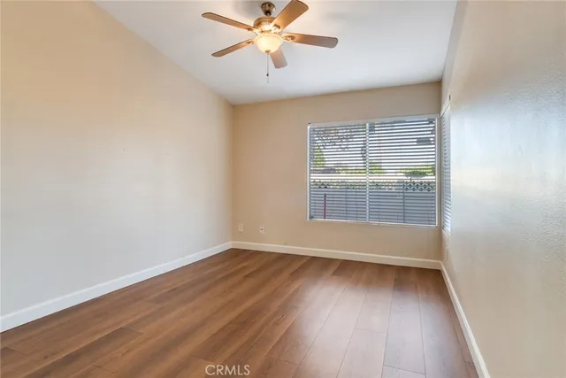 an empty room with wooden floor fan and windows