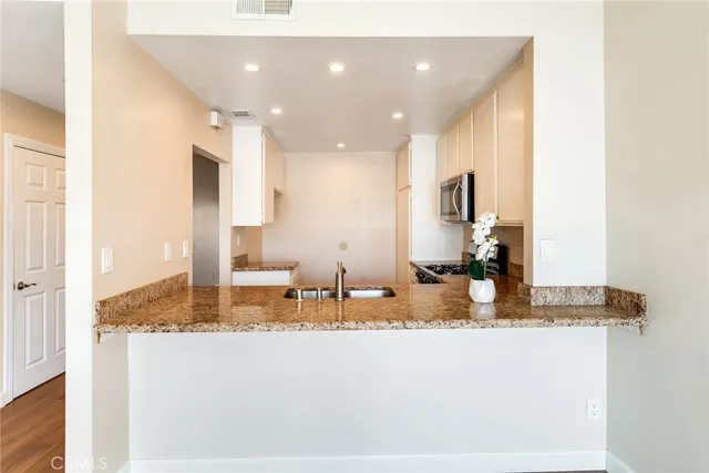 a kitchen with kitchen island granite countertop a sink and a refrigerator