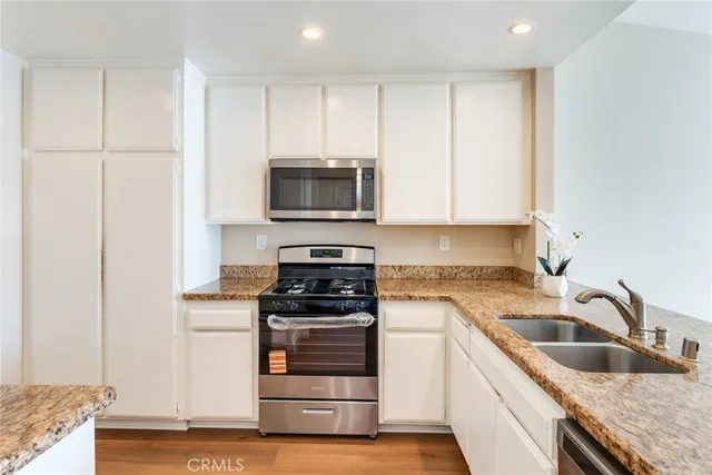 a kitchen with granite countertop a sink and steel appliances
