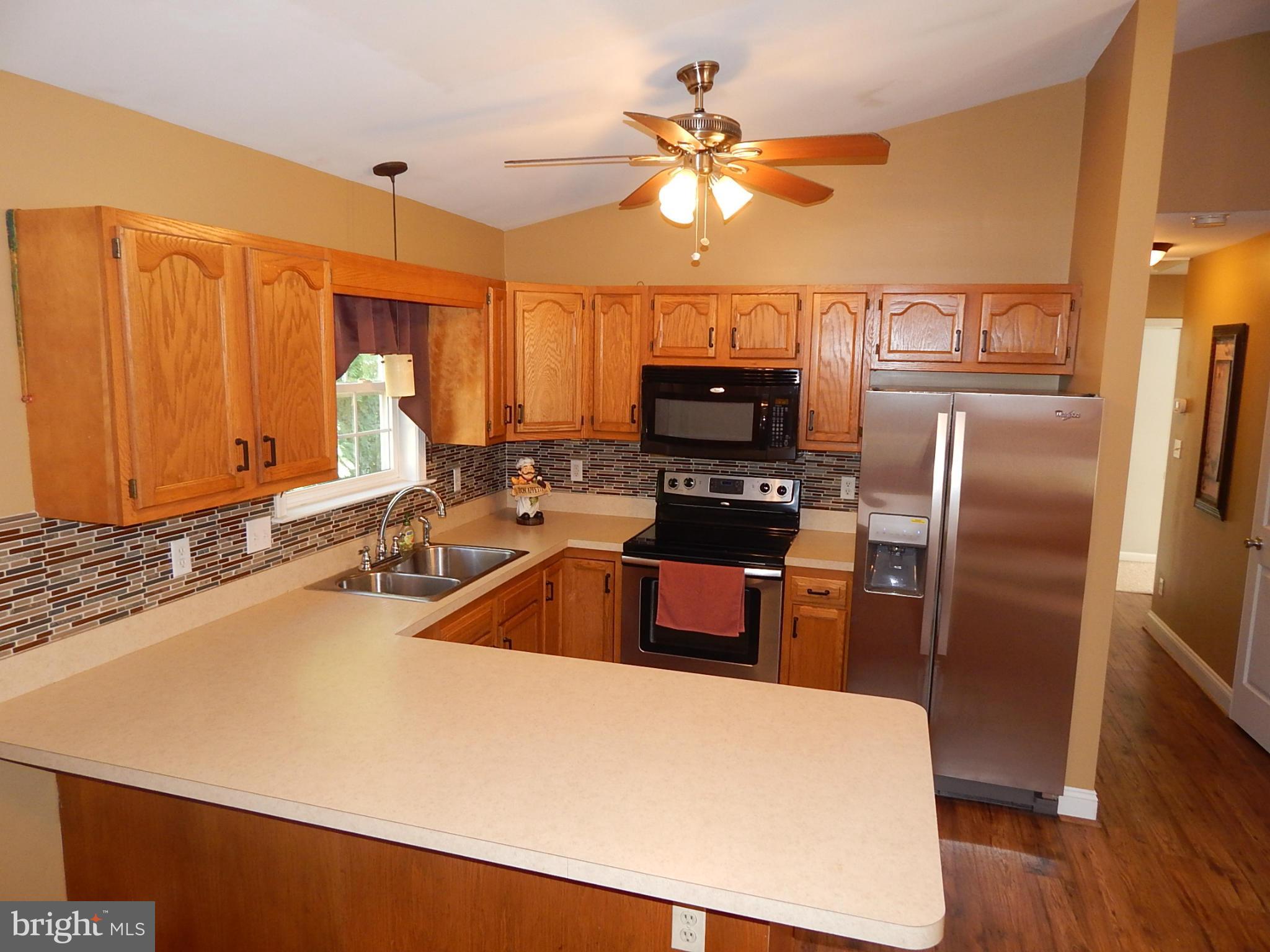1615 Lottie Fowler Road Prince Frederick, MD 20678 - Photo 5 of 29 a kitchen with stainless steel appliances a sink a stove a refrigerator with a dining table and chairs