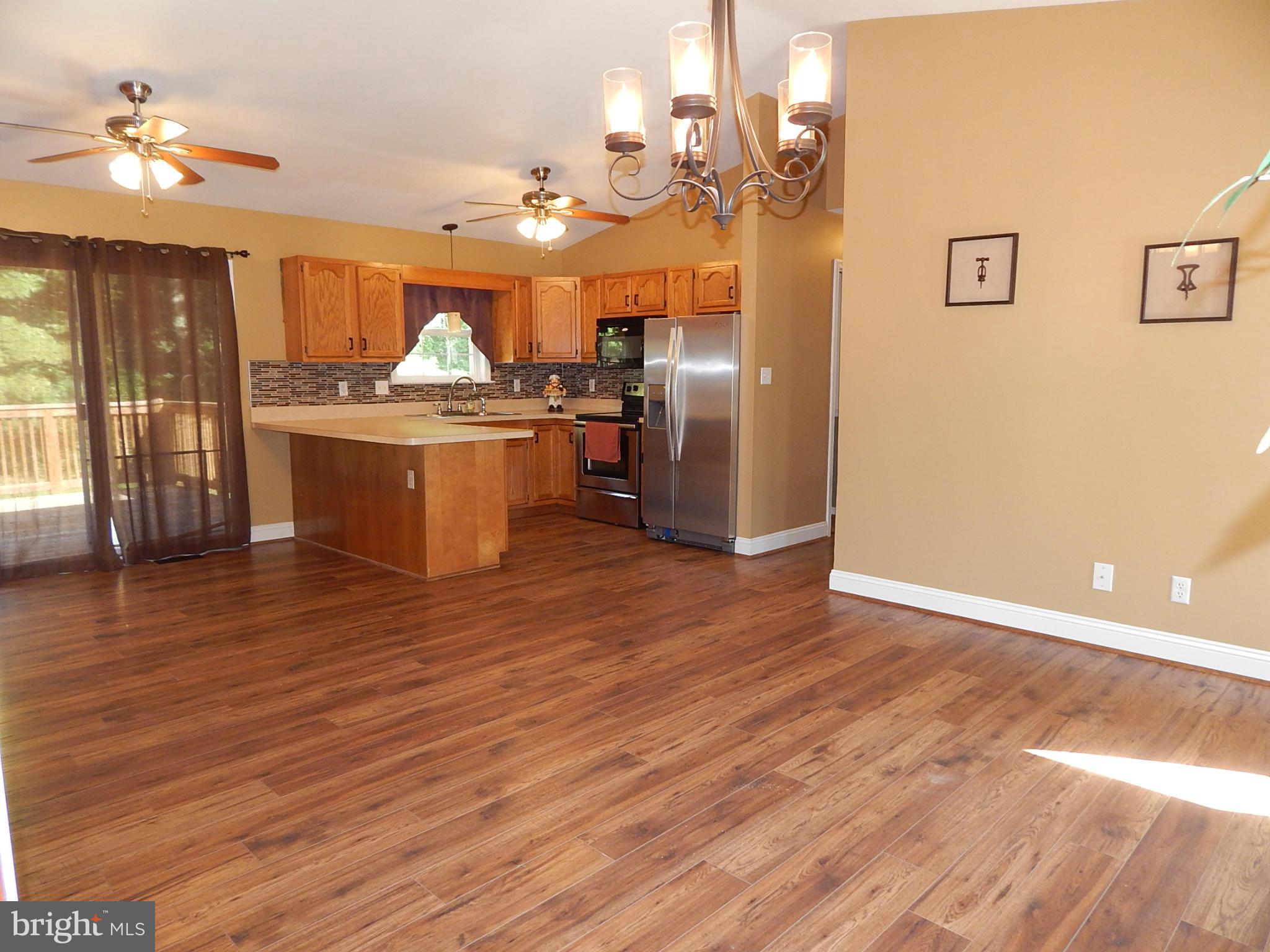 1615 Lottie Fowler Road Prince Frederick, MD 20678 - Photo 6 of 29 a kitchen with stainless steel appliances granite countertop a refrigerator a sink dishwasher a stove and a dining table with wooden floor