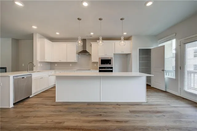 a large kitchen with cabinets wooden floor and stainless steel appliances