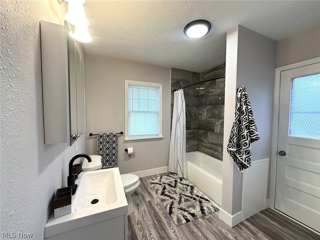 Full bath featuring vanity, a textured ceiling, light wood-style flooring, and shower / bath combo