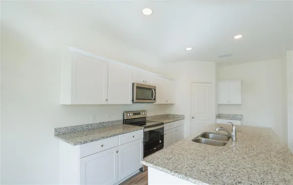 a kitchen with granite countertop a sink and a stove top oven