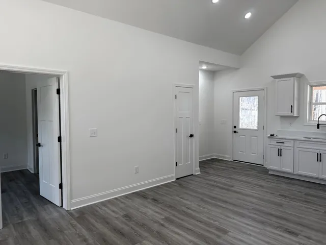 an empty room with wooden floor cabinet and windows