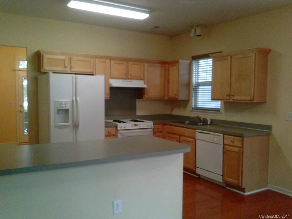 a kitchen with stainless steel appliances granite countertop a refrigerator a stove and a sink