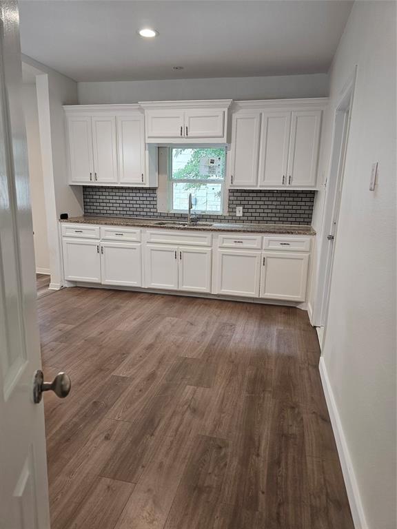1704 Proctor Avenue Waco, TX 76708 - Photo 16 of 23 a kitchen with granite countertop wooden floors white cabinets and wooden floor