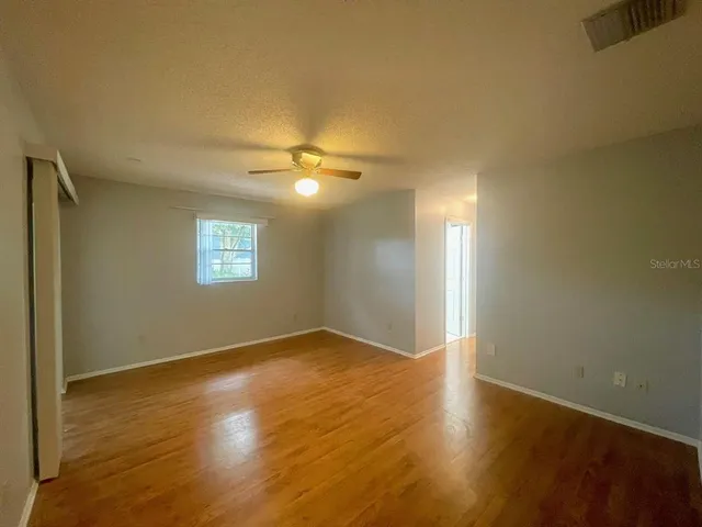 an empty room with wooden floor and chandelier fan