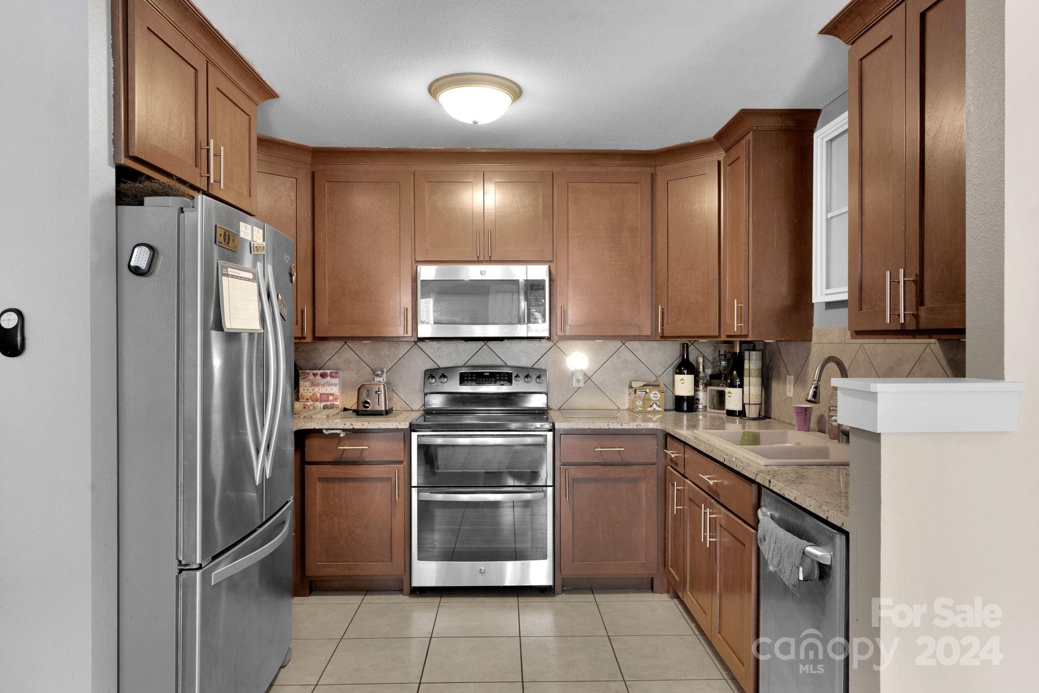 738 Sinclair Drive Monroe, NC 28112 - Photo 11 of 33 a kitchen with stainless steel appliances granite countertop white cabinets a stove top oven a sink and dishwasher