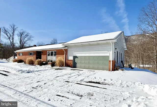 a front view of a house with a yard covered in snow