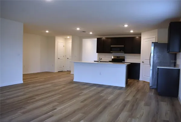 a open kitchen with kitchen island granite countertop a sink and refrigerator