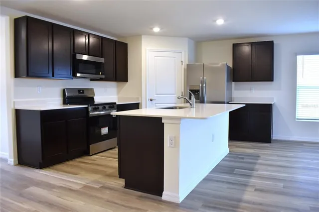 a kitchen with stainless steel appliances kitchen island granite countertop a stove a sink and a microwave