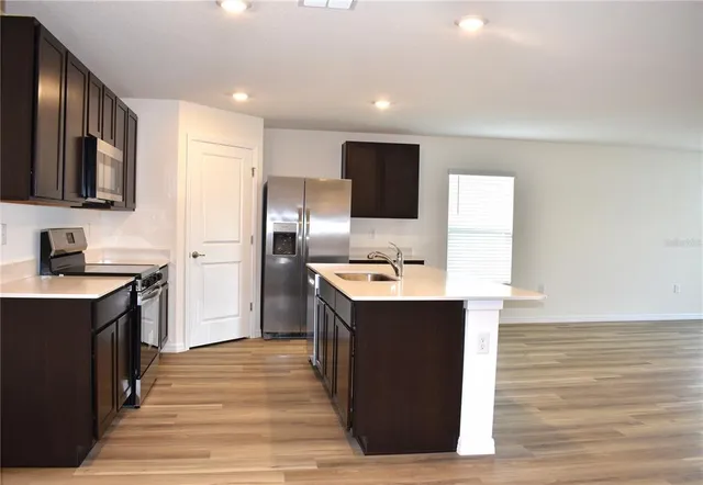 a kitchen with stainless steel appliances a stove top oven a sink a refrigerator white cabinets and wooden floor