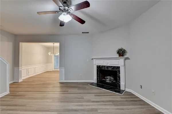 a view of an empty room with wooden floor fireplace and a window