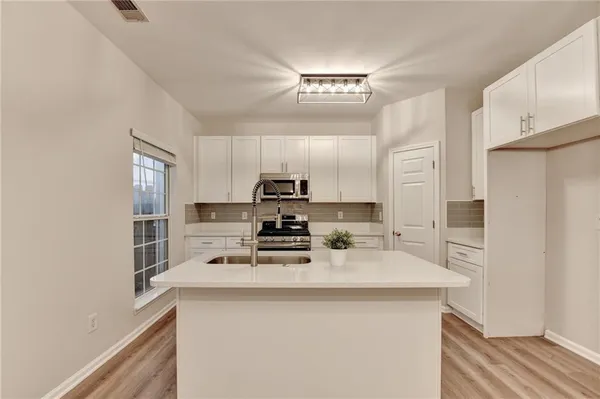 a kitchen with a refrigerator a stove a sink and white cabinets