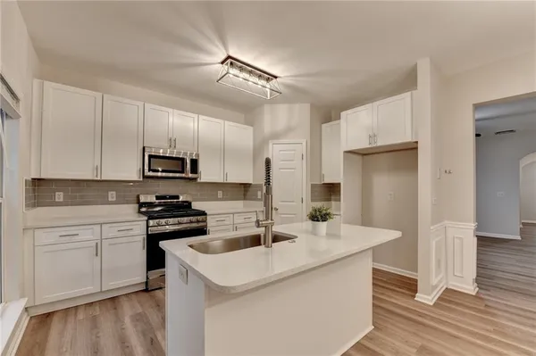 a kitchen with stainless steel appliances a sink a stove a refrigerator and cabinets