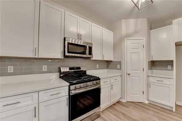 a kitchen with white cabinets and appliances
