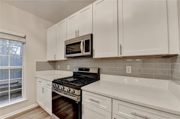 a kitchen with granite countertop white cabinets and stainless steel appliances