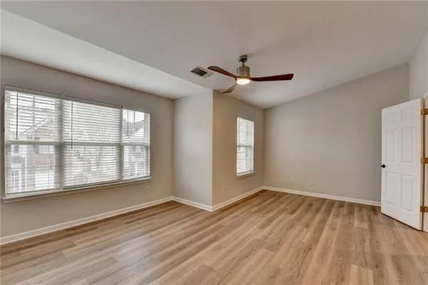 a view of empty room with wooden floor and fan