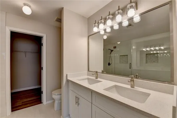 a bathroom with a sink a toilet and a large mirror