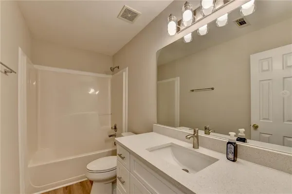 a bathroom with a sink a toilet a mirror and shower