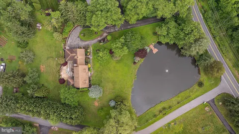 an aerial view of residential house with outdoor space and trees all around