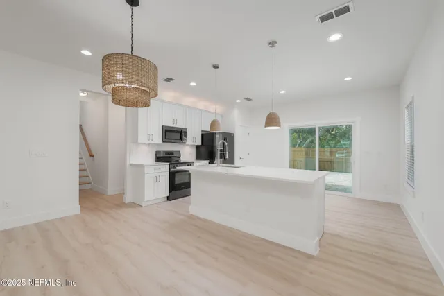 a open kitchen with kitchen island white cabinets and stainless steel appliances