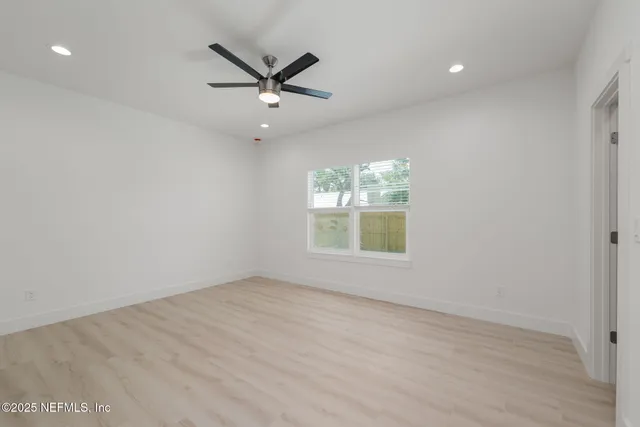 an empty room with windows and ceiling fan