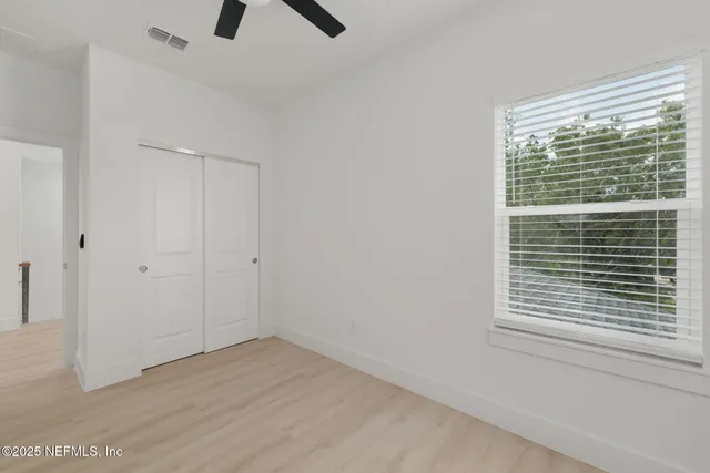 a view of an empty room with a window and a ceiling fan