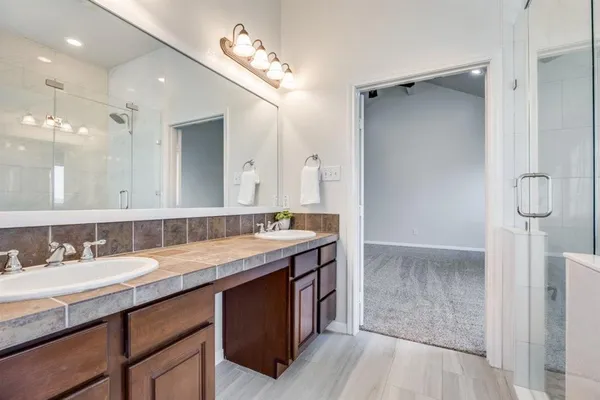 a bathroom with a granite countertop sink a large mirror and a shower