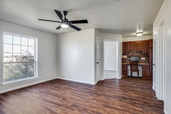 a view of a kitchen with wooden floor a ceiling fan and windows