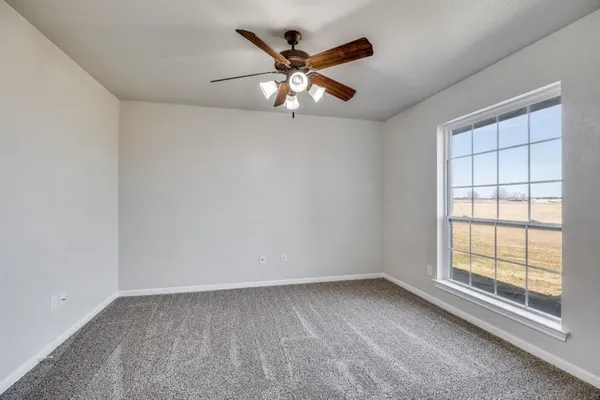an empty room with chandelier fan and windows