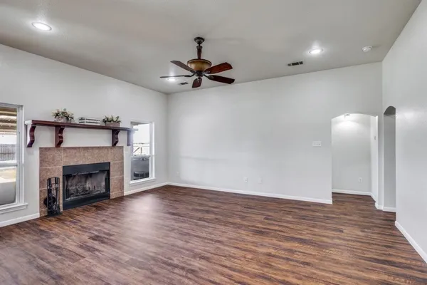 a view of an empty room with wooden floor fireplace and a window