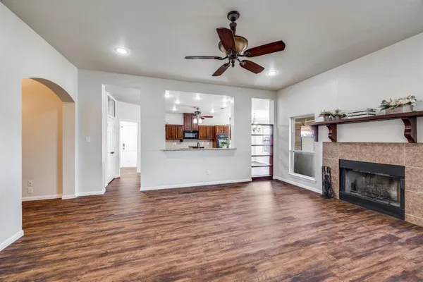a view of a living room a kitchen with wooden floor and a ceiling fan