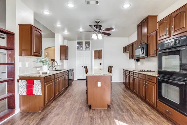 a kitchen with stainless steel appliances granite countertop a sink stove and wooden cabinets