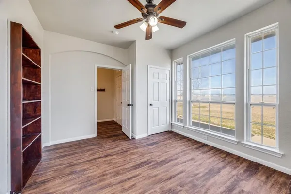 a view of an empty room with a window and wooden floor