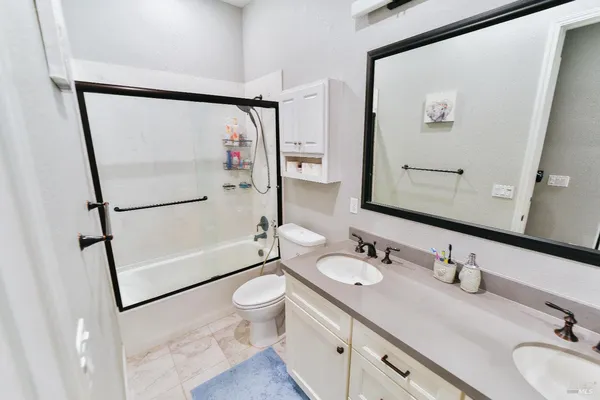 a bathroom with a granite countertop sink mirror vanity and toilet